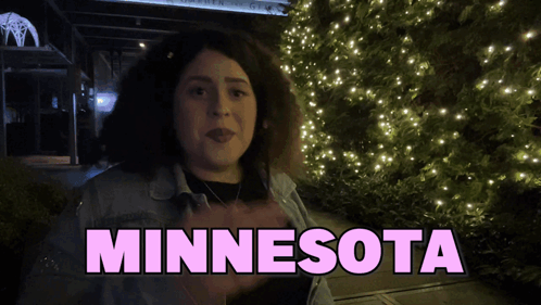 A Woman Is Standing In Front Of A Christmas Tree And The Word Minnesota Is Above Her GIF