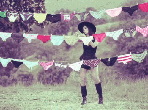 A Woman Is Standing In Front Of A Clothesline With Pink Underwear Hanging From It GIF