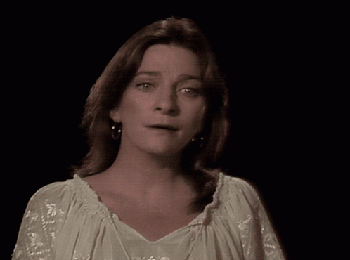 A Woman Is Standing In Front Of A Clown In A Colorful Outfit GIF