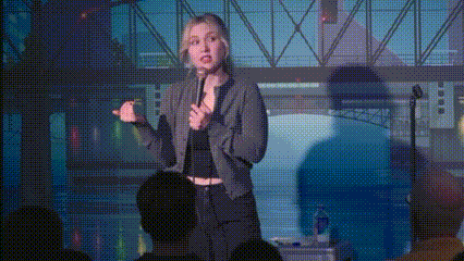A Woman Is Standing In Front Of A Crowd Holding A Microphone And Giving A Speech . GIF