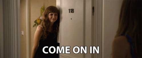 A Woman Is Standing In Front Of A Door That Says 118 And Says Come On In GIF