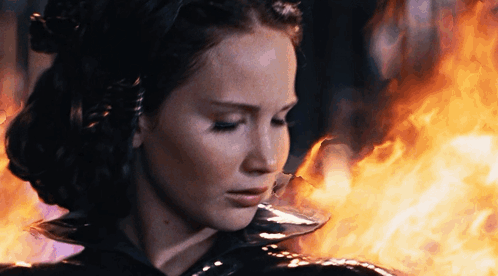 A Woman Is Standing In Front Of A Fire GIF