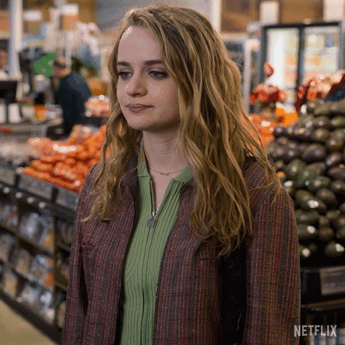 A Woman Is Standing In Front Of A Grocery Store Aisle . GIF