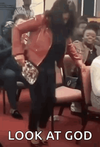 A Woman Is Standing In Front Of A Group Of People And Holding A Purse In Her Hand . GIF