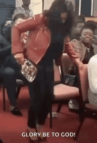 A Woman Is Standing In Front Of A Group Of People In A Church And Dancing . GIF