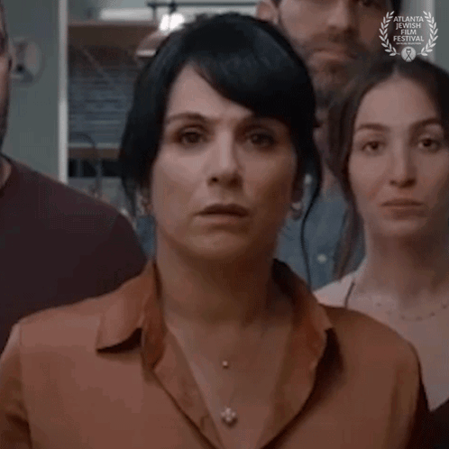 A Woman Is Standing In Front Of A Group Of People With A Laurel Wreath On Her Neck . GIF