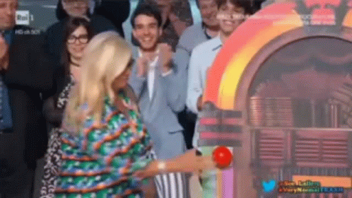 A Woman Is Standing In Front Of A Jukebox In A Crowd Of People GIF