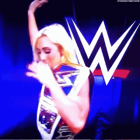 A Woman Is Standing In Front Of A Large W Logo . GIF