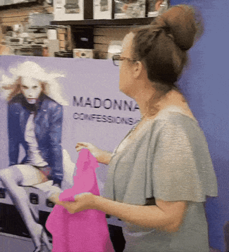 A Woman Is Standing In Front Of A Madonna Confessions Sign GIF