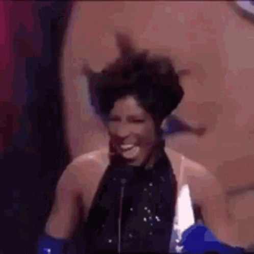 a woman is standing in front of a microphone and laughing .