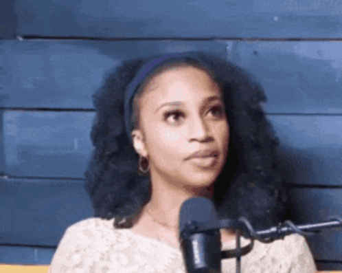 A Woman Is Standing In Front Of A Microphone And Making A Funny Face GIF