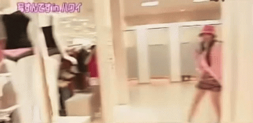A Woman Is Standing In Front Of A Mirror In A Dressing Room In A Store . GIF