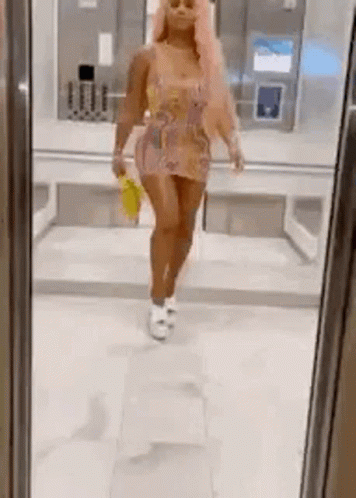 A Woman Is Standing In Front Of A Mirror Wearing A Dress And Holding A Yellow Bag . GIF
