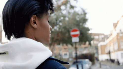 A Woman Is Standing In Front Of A No Entry Sign GIF