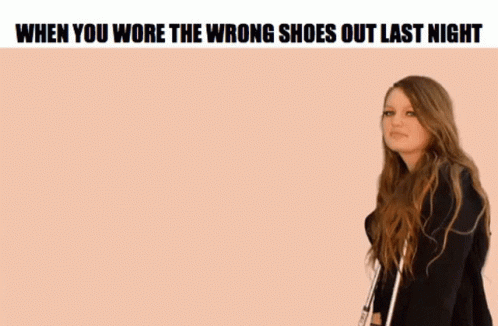 A Woman Is Standing In Front Of A Pink Background With The Words `` When You Wore The Wrong Shoes Out Last Night '' On I GIF