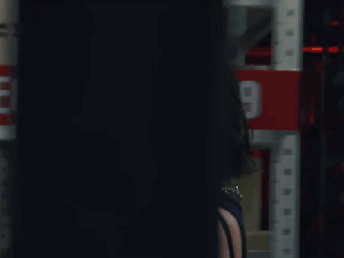 A Woman Is Standing In Front Of A Red Sign That Says 2 GIF