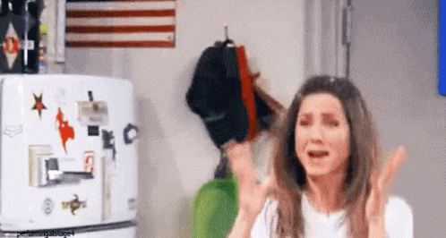 A Woman Is Standing In Front Of A Refrigerator With Stickers On It And Crying . GIF