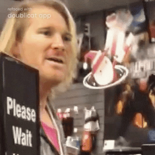 A Woman Is Standing In Front Of A Sign That Says Please Wait . GIF