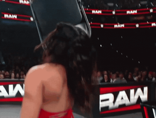 A Woman Is Standing In Front Of A Sign That Says Raw GIF