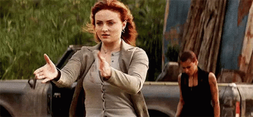 A Woman Is Standing In Front Of A Truck With Her Arms Outstretched In A Karate Pose . GIF