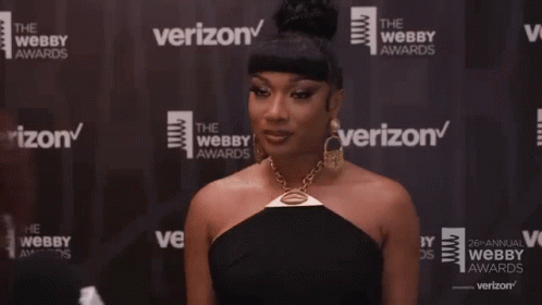 A Woman Is Standing In Front Of A Verizon Banner GIF