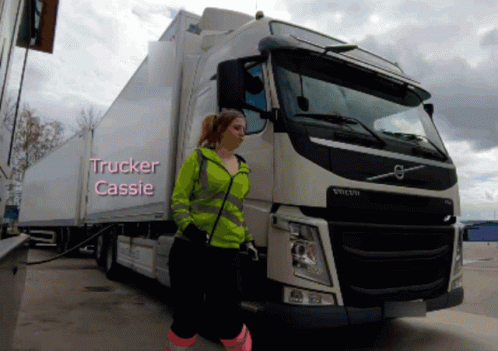 A Woman Is Standing In Front Of A Volvo Truck With The Name Trucker Cassie Written On It GIF