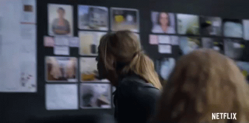 A Woman Is Standing In Front Of A Wall With Pictures On It And A Netflix Logo In The Corner . GIF