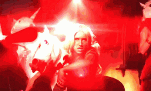 A Woman Is Standing In Front Of A White Unicorn GIF