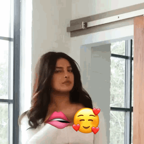 A Woman Is Standing In Front Of A Window With A Smiley Face On Her Chest GIF