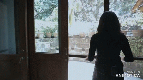 A Woman Is Standing In Front Of A Window With The Words Made In Animotica On The Bottom GIF