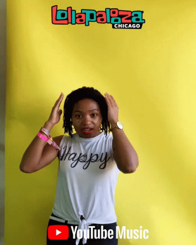 A Woman Is Standing In Front Of A Yellow Background That Says ' Lolapaloza Chicago ' On It GIF