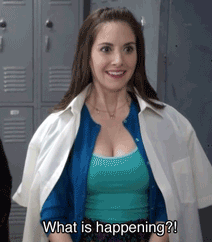 A Woman Is Standing In Front Of Lockers And Smiling While Asking What Is Happening . GIF