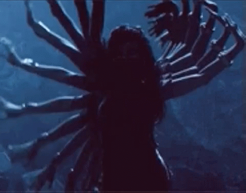 A Woman Is Standing In The Dark With A Bunch Of Arms . GIF
