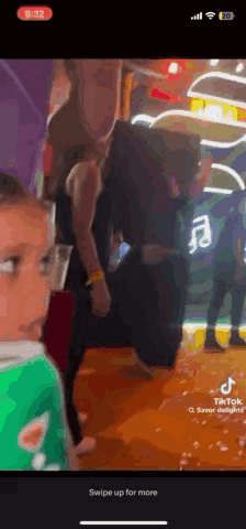 A Woman Is Standing Next To A Child In A Green Shirt In A Room . GIF