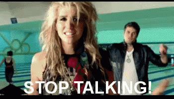 A Woman Is Standing Next To A Man In A Bowling Alley With The Words `` Stop Talking '' Written On The Screen . GIF