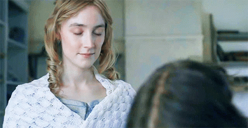 A Woman Is Standing Next To Another Woman With Her Eyes Closed And A White Blanket On Her Shoulders . GIF