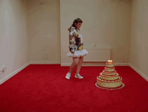 A Woman Is Standing On A Cake That Has Candles On It GIF