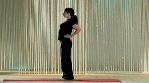 A Woman Is Standing On A Mat With Her Hands On Her Hips . GIF