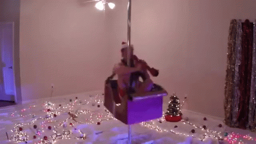 A Woman Is Standing On A Pole In A Room With Christmas Lights . GIF