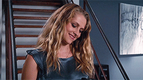 A Woman Is Standing On A Set Of Stairs And Smiling GIF