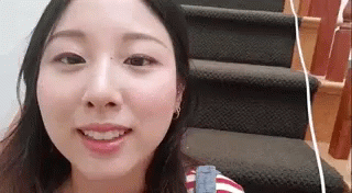 A Woman Is Standing On A Set Of Stairs Smiling . GIF