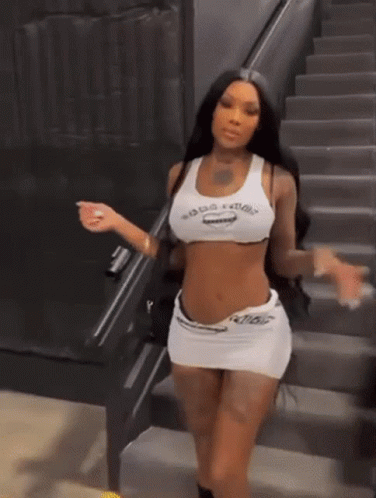 a woman is standing on a set of stairs wearing a crop top and skirt .