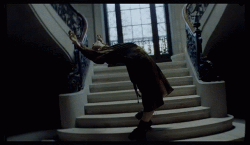 A Woman Is Standing On A Set Of Stairs With Her Arms Outstretched GIF