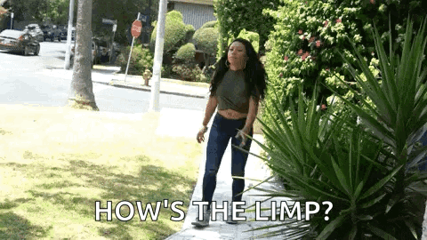 A Woman Is Standing On A Sidewalk With The Words `` How 'S The Limp '' Written Above Her . GIF