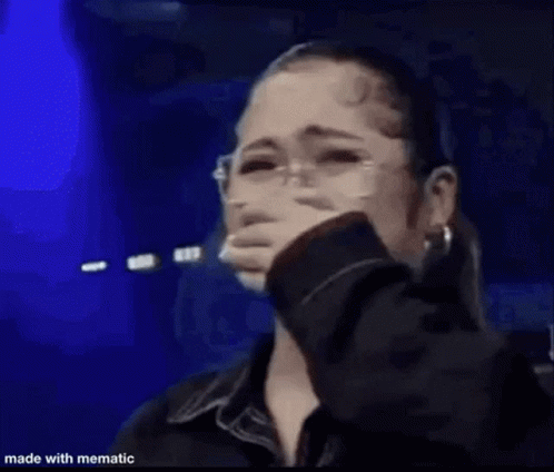 A Woman Is Standing On A Stage Holding A Microphone . GIF
