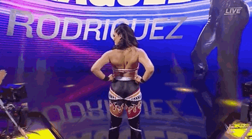 A Woman Is Standing On A Stage In Front Of A Sign That Says Rodriguez GIF