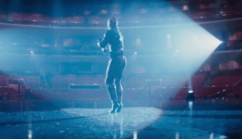 A Woman Is Standing On A Stage In Front Of An Empty Auditorium GIF
