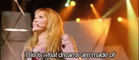 A Woman Is Standing On A Stage With A Microphone In Her Mouth . GIF