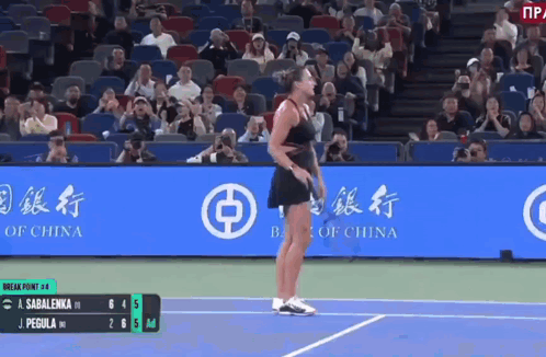 A Woman Is Standing On A Tennis Court In Front Of A Bank Of China Banner GIF
