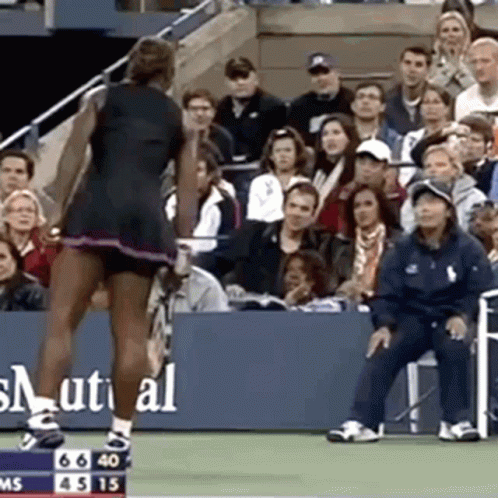 A Woman Is Standing On A Tennis Court In Front Of A Crowd Of People . GIF